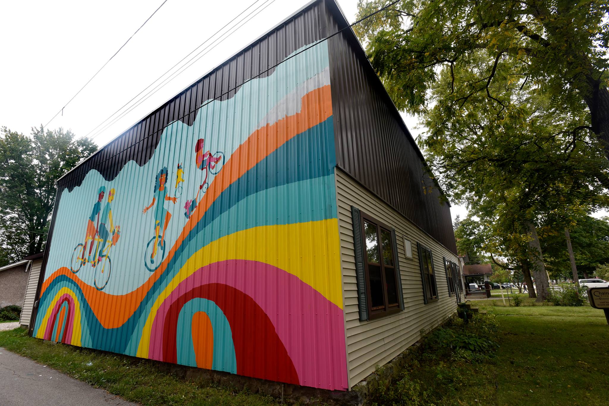 A mural on the side of the building depicts a family of cyclists in vibrant colors.